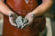 © primipil - Man sculptor dressed leather apron with clay in hands. Statue craft creation workshop.