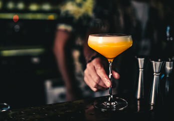 Wall Mural - man hand bartender holding cocktail in glass on the bar counter