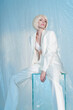 Studio fashion photo of young elegant woman in white men's jacket