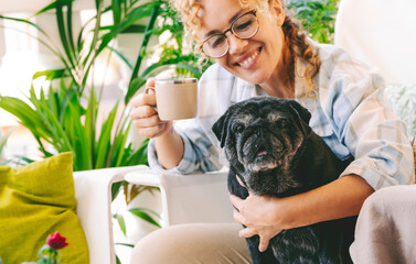 Animal dog best friend together concept with happy young woman owner hug with love and friendship her adorable black pug puppy outdoor at home in the garden. Cheerful female with cute pet in relax