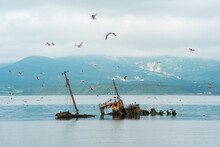 Shipwreck Against The Backdrop Of A Sea Bay With Foggy Mountains In The Background