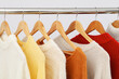 © Atlas - Wardrobe rack with hangers with sweaters on light background