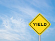 Yellow transportation sign with word yield on blue color sky background