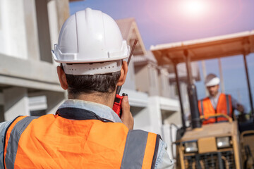 Poster - Professional worker talking by walkie talkie checking and working at construction site of the housing project.