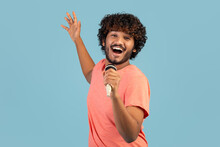 Joyful Indian Guy Singing Karaoke On Blue, Holding Microphone