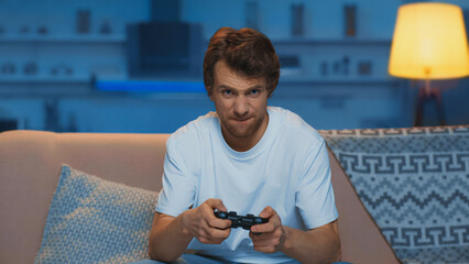 KYIV, UKRAINE - AUGUST 31, 2022: concentrated young man playing video game in living room