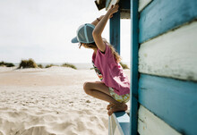 Girl Hanging From A Beach Hut Checking The Surf On A Sunny Day