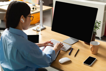 Unrecognizable Korean Woman Using Computer With Empty Screen In Office