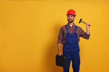 Poster - Professional builder in uniform with hammer and toolbox on yellow background, space for text