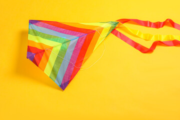 Wall Mural - Bright rainbow kite on yellow background, top view