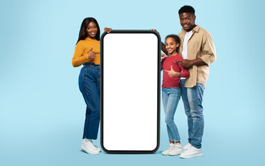 Great offer concept. Happy black family pointing at giant smartphone with white blank screen mockup