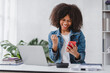 Leinwandbild Motiv successful and exciting african american businesswoman Young woman excited to win on her smartphone at work.
