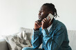© Prostock-studio - Serious Black Guy Talking On Phone Sitting At Home