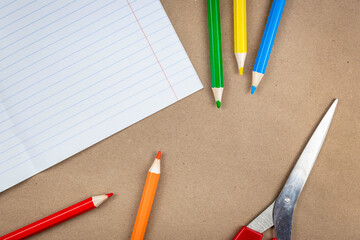 School supplies and a notebook lie on a textured brown paper background