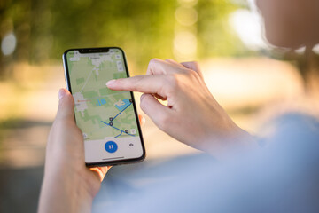 girl cyclist looks at a map on her phone and plots a route for a trip for a gps navigator