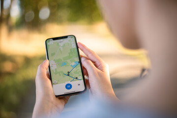 girl cyclist looks at a map on her phone and plots a route for a trip for a GPS navigator