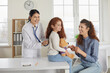 © Studio Romantic - Happy mother and child come to family doctor for checkup. Pretty little patient sitting on table in modern medical office and holding teddy bear while cheerful smiling pediatrician examines her lungs