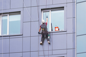 a window cleaner works on the facade of a high-rise office building. industrial alpinism. young man 