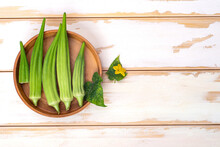 Green Okra Pods In Wooden Bowl On A White Table.Copy Space.