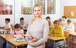 © JackF - Portrait of positive female school teacher posing in classroom with her pupils on background