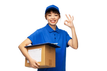 Wall Mural - profession, job and people concept - happy smiling delivery woman in blue uniform holding parcel box showing ok gesture over white background