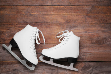 Wall Mural - pair of white ice skates on wooden background, flat lay