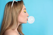 © New Africa - Fashionable young woman with bright makeup blowing bubblegum on light blue background, space for text