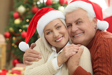 Wall Mural - Happy mature couple in Santa hats at home. Christmas celebration