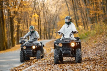 Man and woman driving quad bike in autumn forest