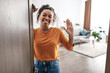 © Prostock-studio - Joyful African American Lady Waving Hello Opening Door At Home