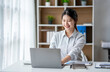 © crizzystudio - Young woman working on a laptop in the office. Asian businesswoman sitting at her workplace in the office.  Beautiful Freelancer Woman working online at her home.