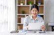 © crizzystudio - Asian business woman taking notes on online meetings on the Internet through a laptop in an open office business idea Data Analysis, Roadmap, Marketing, Accounting, Auditing