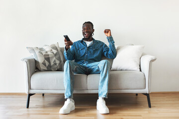 Wall Mural - Excited African American Man Watching TV Shaking Fists At Home