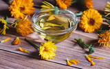 Fototapeta Dmuchawce - Calendula officinalis cosmetic oil, dried and fresh marigold flowers on wooden table