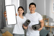 Happy asian family having morning yoga at home, showing smartphone