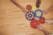 © Deen Jacobs/peopleimages.com - Success, collaboration and teamwork, people with gears on a wooden table. Diversity, hands and a team of business people working together. Planning, strategy and cooperation for solution in an office