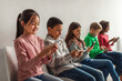 © Prostock-studio - Multiethnic School Kids Using Mobile Phones Sitting Over Gray Background