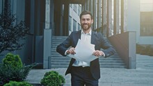 Happy businessman walking outdoors reading report browsing documents reads good news excited motivated satisfied man celebrating victory throwing papers enjoying success rejoices profitable contract