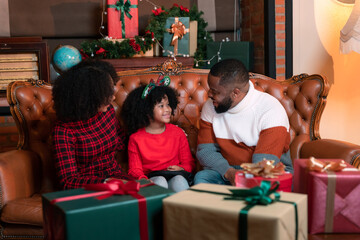 Father, mother and child family rejoicing in the joy of opening a gift box on Christmas Day.