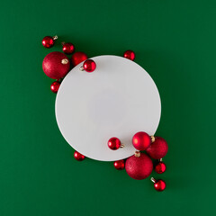 Wall Mural - Creative flat lay holiday background made with Christmas baubles and frame on green background. Minimal New year concept.