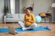 © Prostock-studio - Happy young pregnant african american woman with big belly watching video workout lesson on laptop