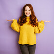 © contrastwerkstatt - laughing redhead woman holding her hands up, copyspace with purple background