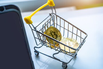 Close-up of Golden bitcoins or cryptocurrency coin or symbols in shopping cart and tablet in white table. Future currency concept.