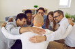 © Studio Romantic - Team of successful positive colleagues laughing and hugging while standing in circle in office. Cheerful business colleagues celebrate their success together. Concept of cohesion and teamwork.