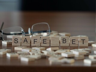 Wall Mural - safe bet word or concept represented by wooden letter tiles on a wooden table with glasses and a book