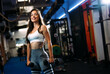 Young fit beautiful woman doing exercises with dumbbell in fitness club.