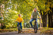 © Maria Moroz - Happy father and daughter ride bicycles in autumn park on sunny day.