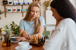© Drobot Dean - White young women playing chess while drinking tea in cafe