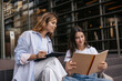 © Look! - Calm young caucasian girls give each other advice studying together sitting on campus. Brunette and blonde wear casual clothes. Study concept