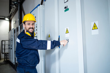 Wall Mural - Portrait of smiling caucasian electrics standing by electrical cabinets.